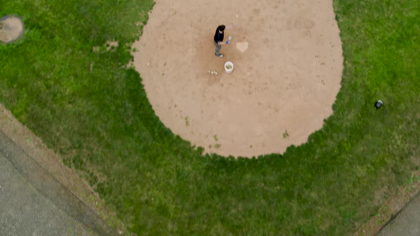 Low traverse over batter hitting a bucket of balls at a baseball diamond