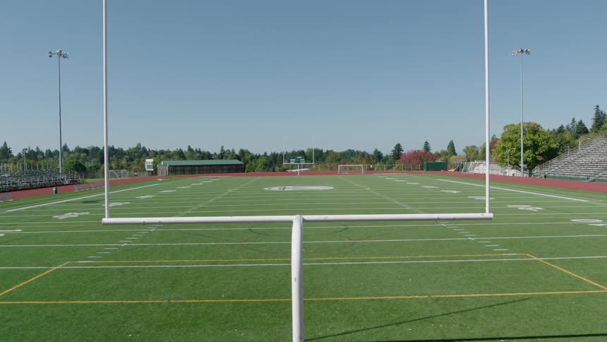 Flying through the upright towards an empty football field on a sunny autumn day