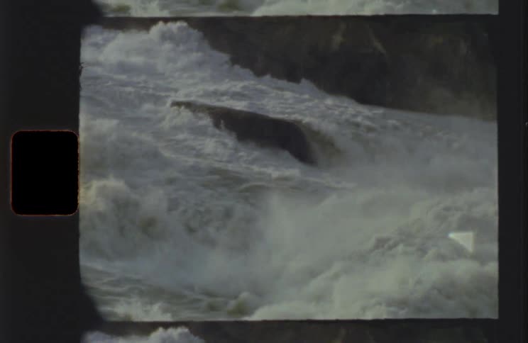 Whitewater rapids crash over a massive rock in the river
