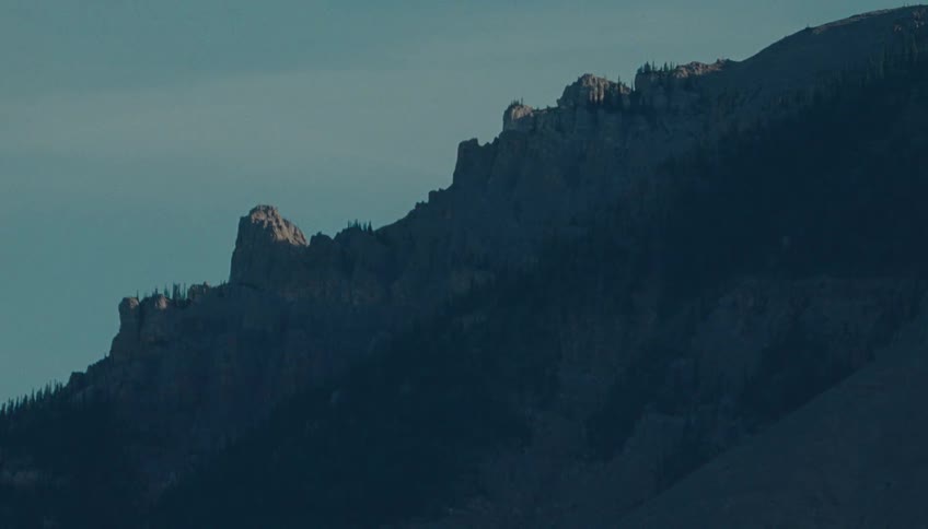 Sharp rocky mountain cliffs rise high against the sky