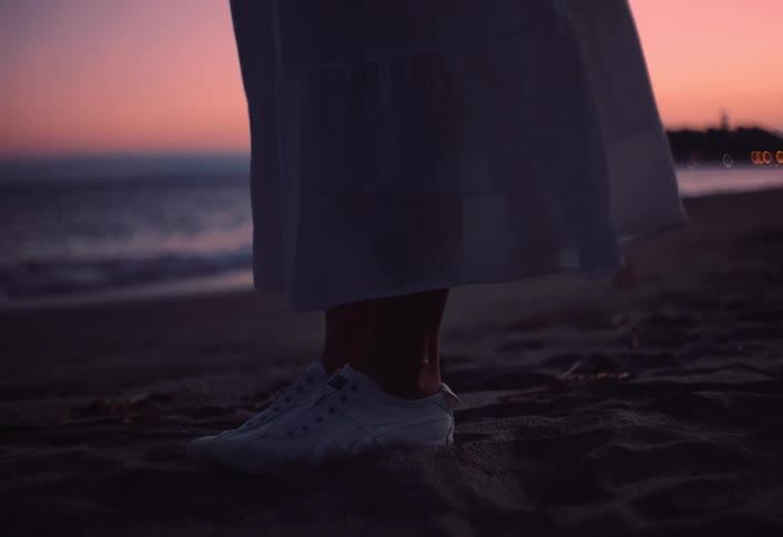 The woman stands on the beach at sunrise