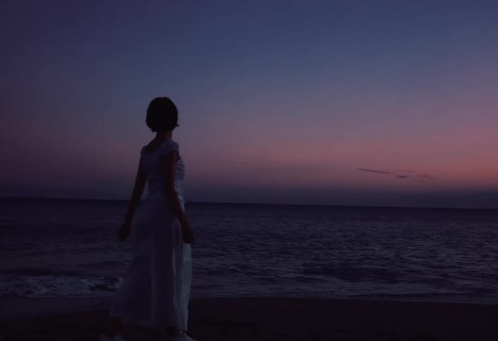 A young asian woman walking on the beach at sunset