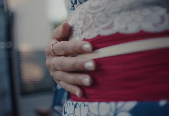The woman traces her hand across the sash on her kimono