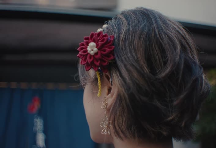 Closeup of a womans side profile with a floral hair accessory