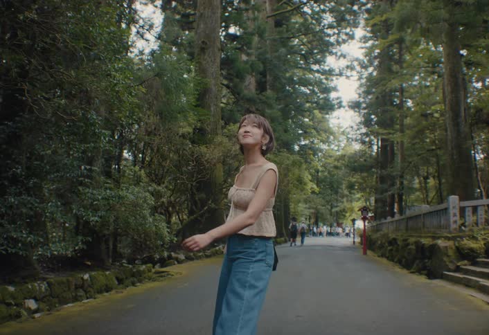 A young woman walks down a path that is surrounded by trees