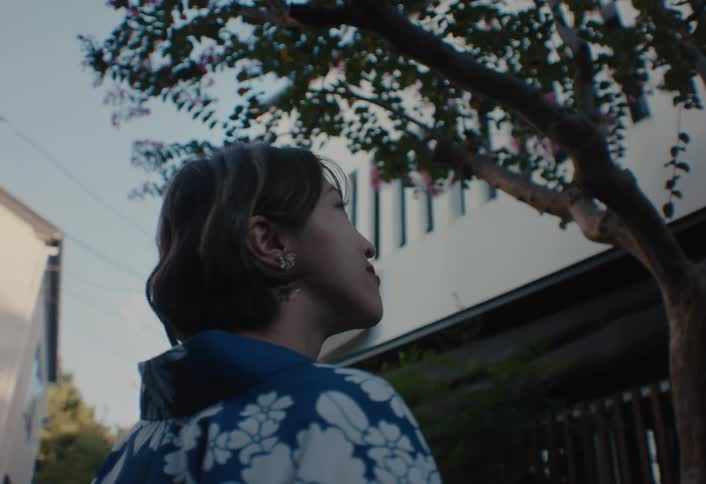 Woman wearing a blue kimono looking at the trees on a residential street