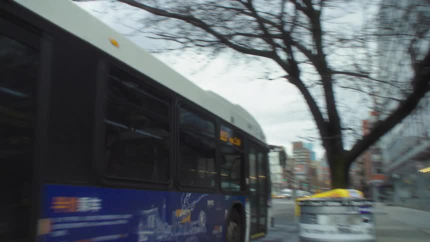 A public bus travels down a road in a metropolitan city