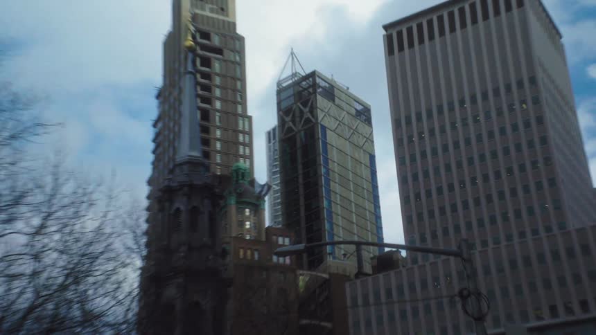 Skyscrapers rise tall in the busy city beneath a partly cloudy sky