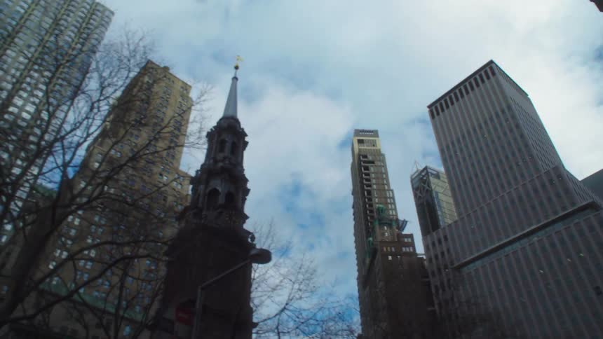One world trade center towers over other city buildings including a cathedral on a cloudy winter day