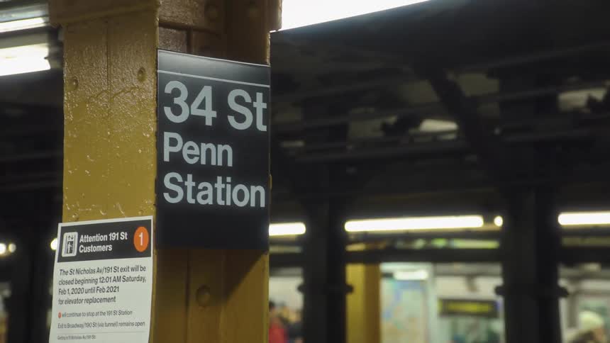 A subway station and a train enters a station the camera focus on a sign