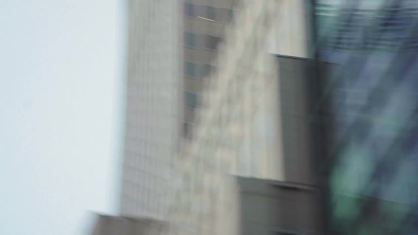 A tall modern skyscraper rises between two buildings against the sky