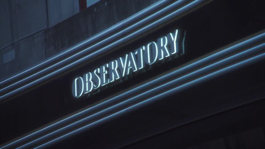 Illuminated sign with the word observatory is mounted on concrete building