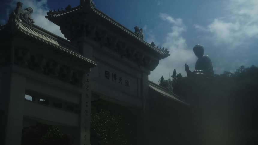 A large traditional temple gate with a massive buddha statue in the background