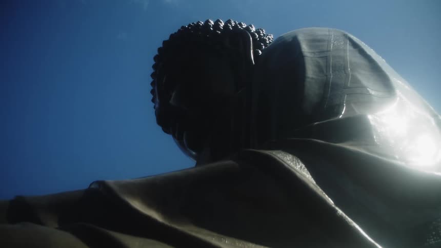 A statue of a chinese monk standing outdoors on a sunny day