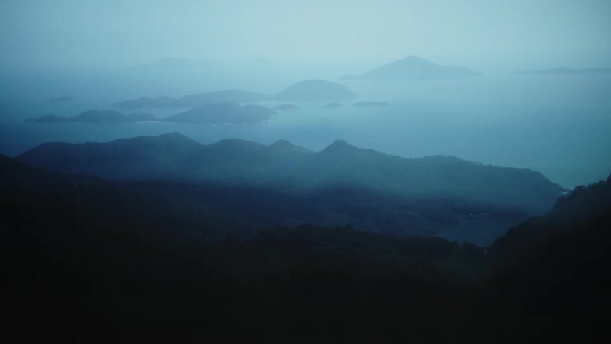Layers of bluish mountains fade into the mist over the sea