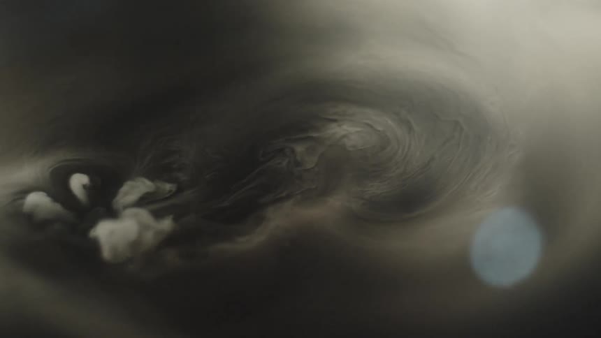 A submerged object spewing whisps of smokes floats under a layer of thick vapor