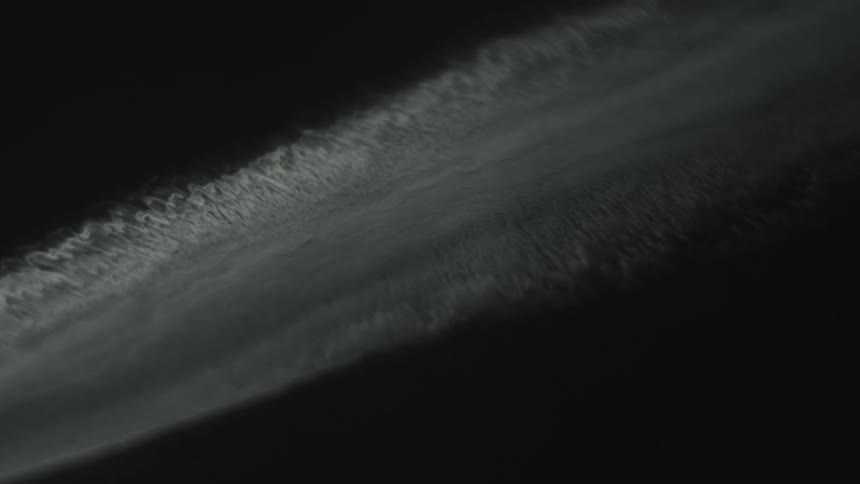 White and dense trail stretches across the dark sky