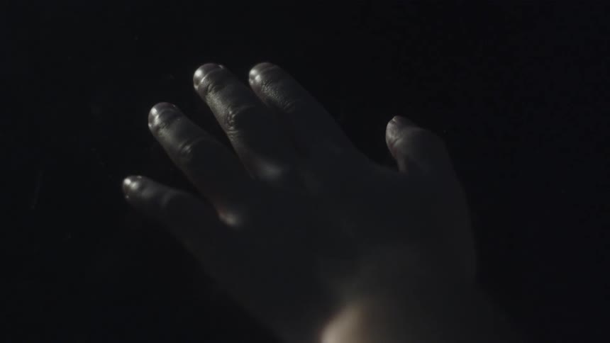 Close up of a persons hand resting and sliding over a dark surface