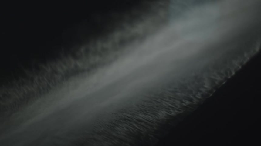 Ocean waves crashing against the shoreline at night seen from an aerial view the moonlight casts a silvery glow over the dark water highlighting the rhythmic motion of the waves as they break and recede along the coast