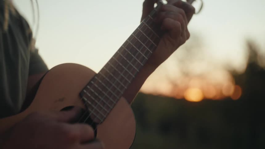 Male playing ukulele in the wilderness at sunset