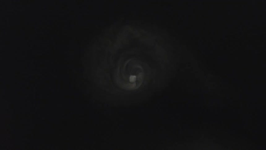 Circular light emerges at the center of a dark spiral surrounded by mist