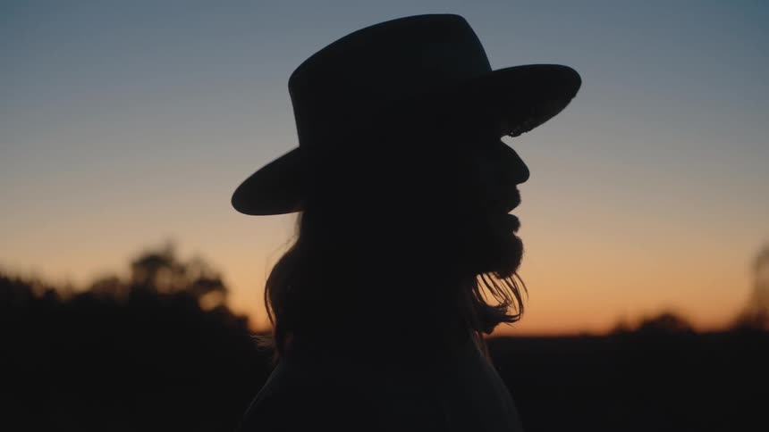 Silhouette of a person wearing a hat at sunset