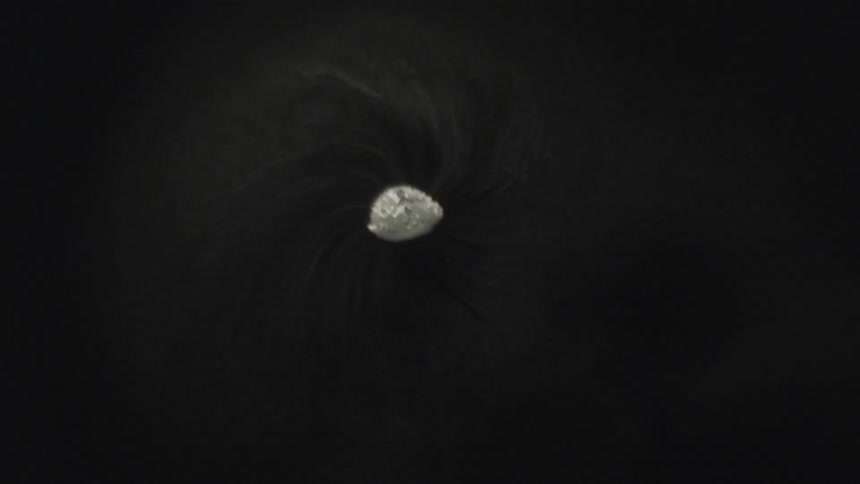 Stream of light smoke expands around a bright core in the dark center