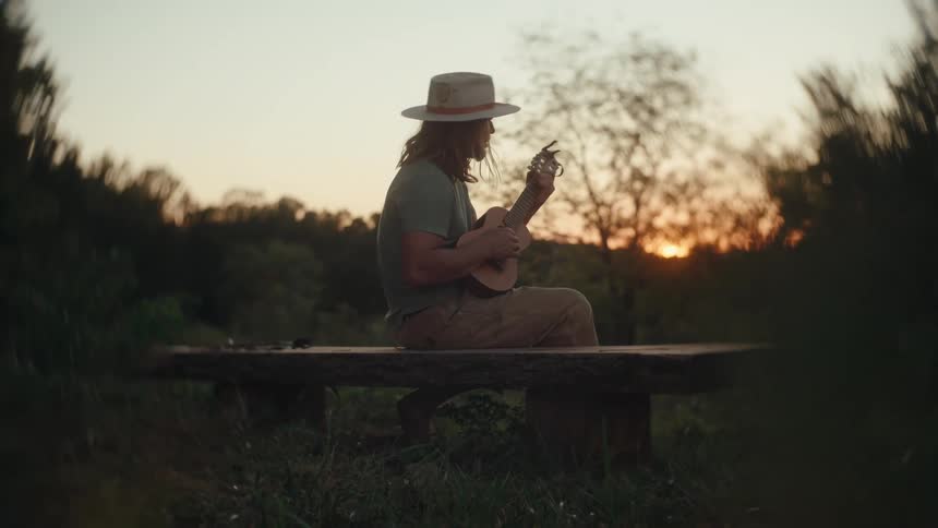 The woman is playing the ukulele at sunrise