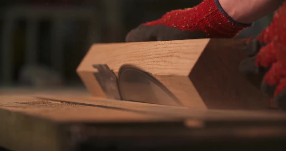 Gloved hands cutting a wooden piece on a circular saw
