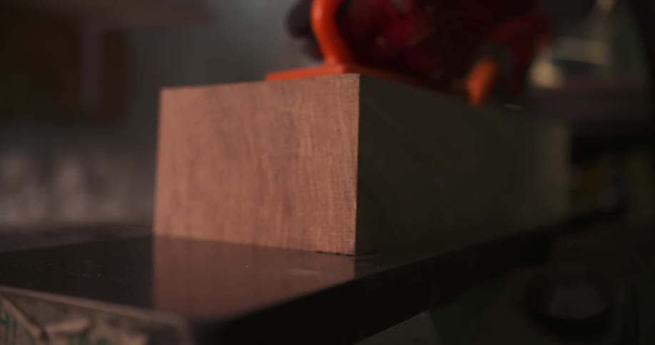 The person cuts a block of wood with a table saw