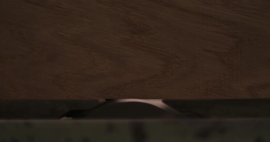 Wooden surface with central inscription rests atop partially visible metallic component