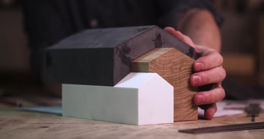 Man adjusts the interconnecting shapes representing an abstract building while working in an office