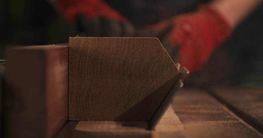 Close up of a carpenter shaping a wood log with a machine in a workshop
