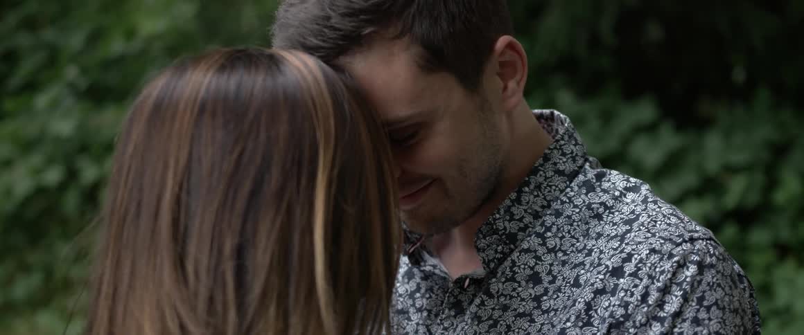 A man kisses a woman on the head and holds her close