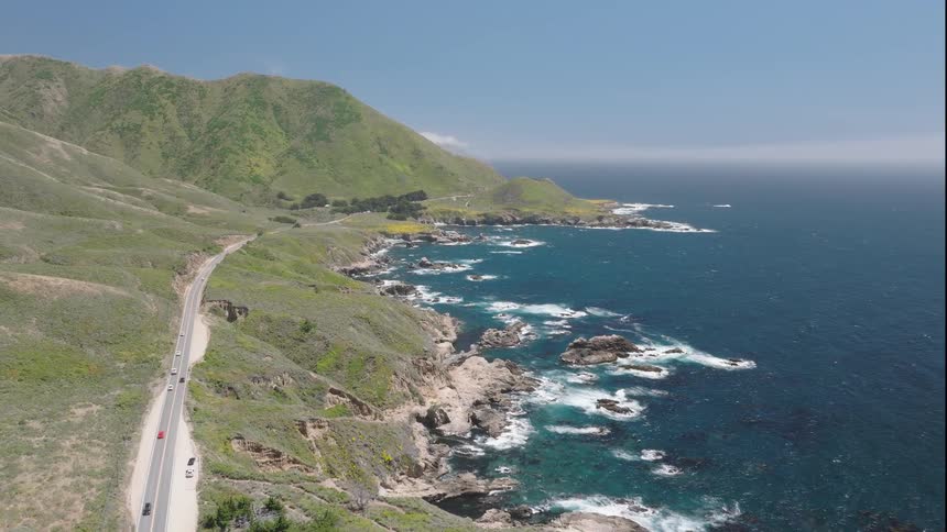 Winding coastal road following green cliffs beside the blue ocean