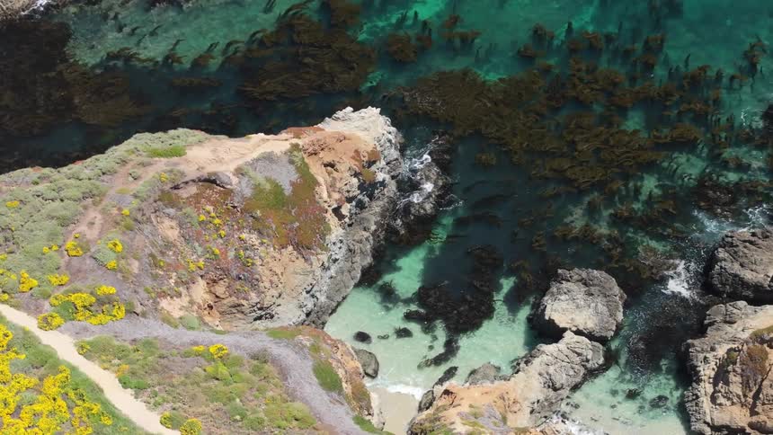 Rocky shoreline reveals crystalclear waters in shades of blue and green where nature meets depth