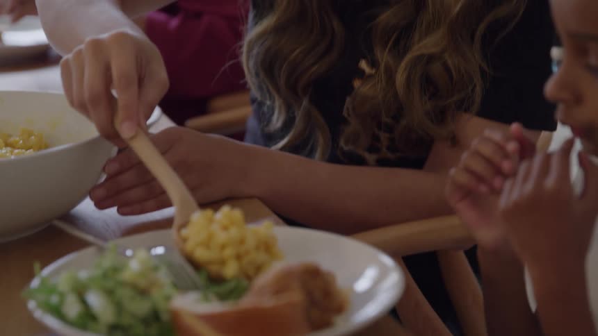 Mother serving mac and cheese onto sons plate