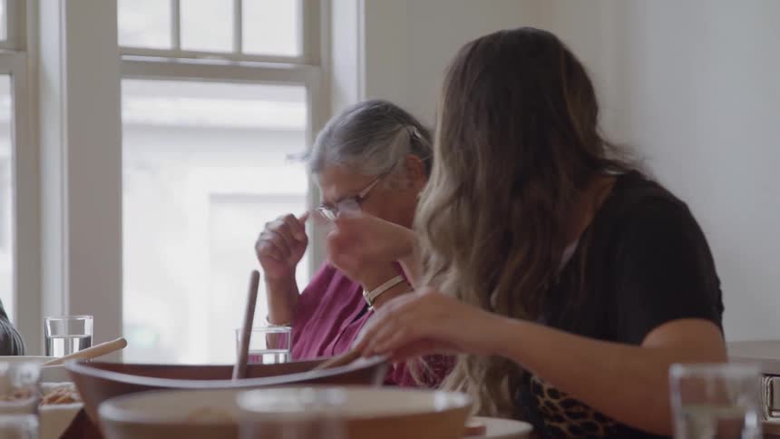 Two women talking and smiling while sharing a meal at the table