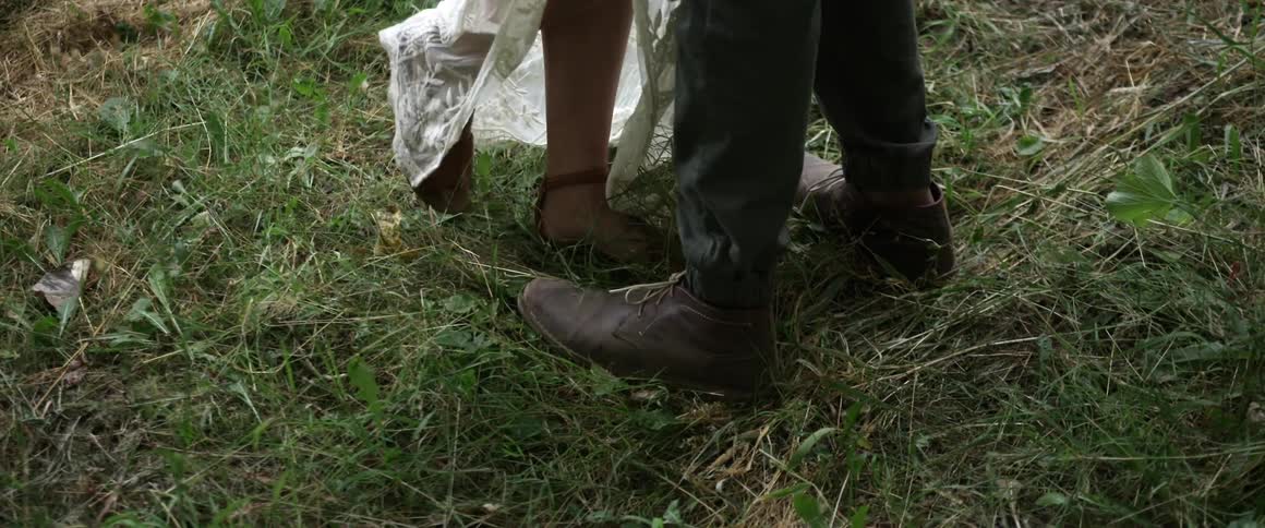 Two pairs of legs stand together in the grass