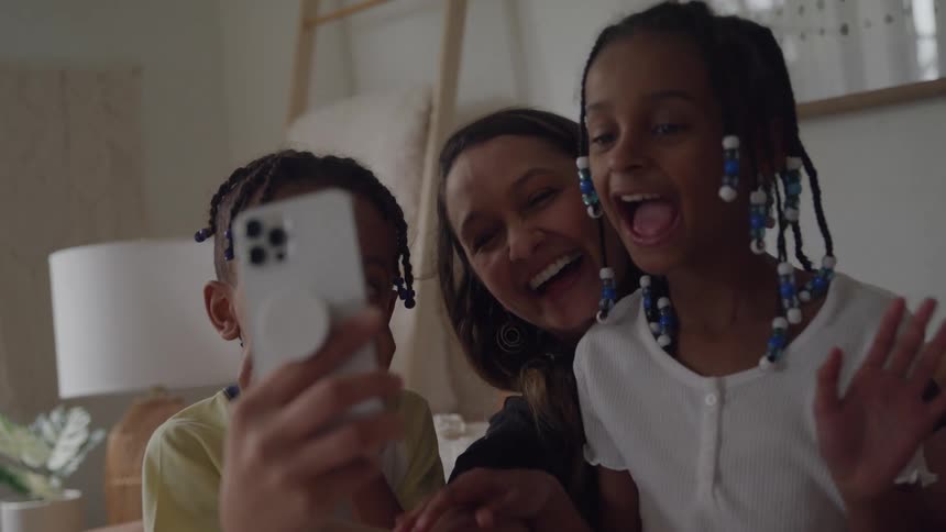 Woman and two children smile together while taking a selfie