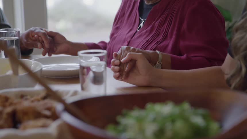 People hold hands around the table before a meal