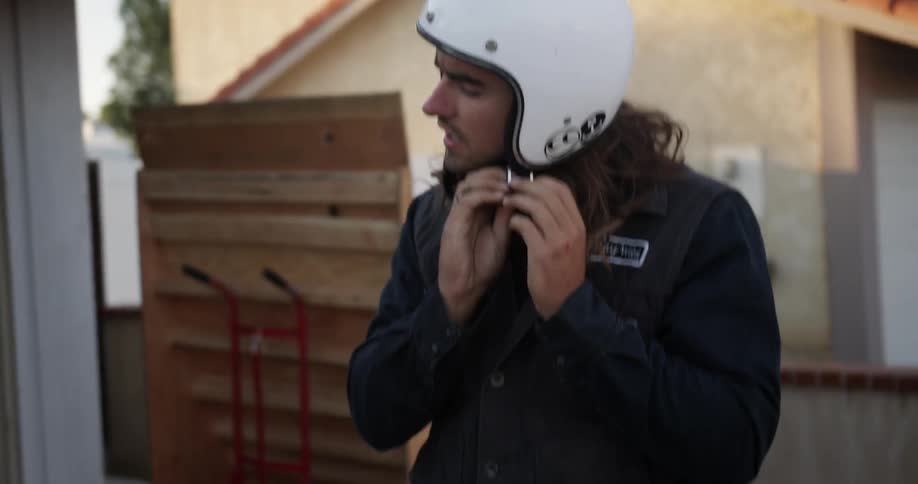 A man is putting on his motorcycle helmet and talking