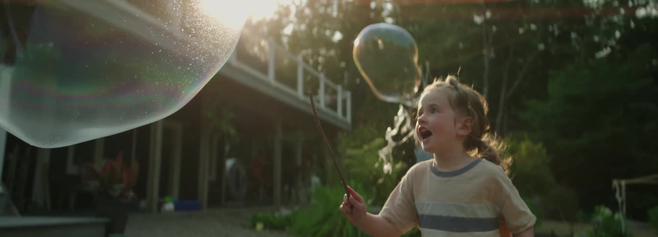 The child chases bubbles in the yard