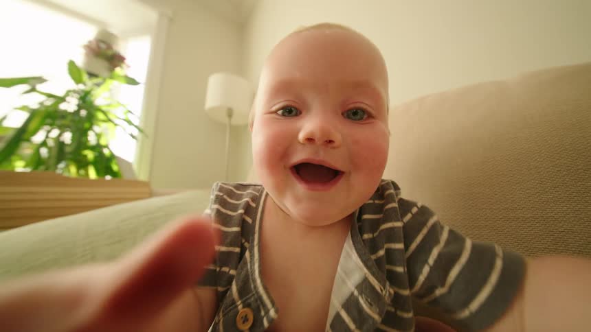 Baby smiles excitedly with arms reaching forward
