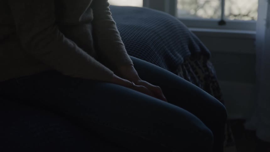 The woman is sitting on the bed
