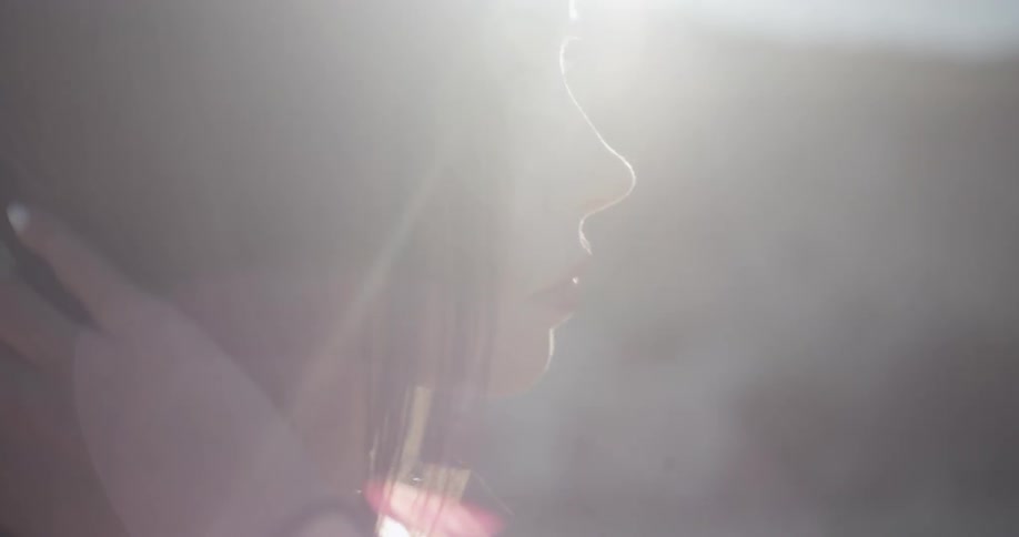 A woman stands under a sunny sky