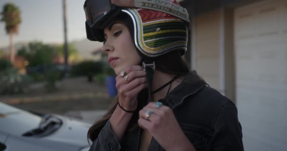 Woman puts on motorcycle helmet and adjusts goggles