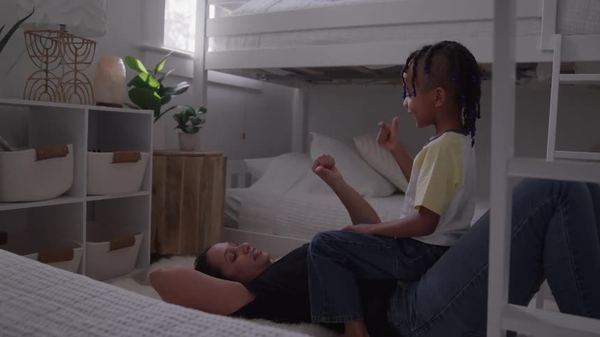 Child sitting on a womans lap lying on the floor playing and smiling together