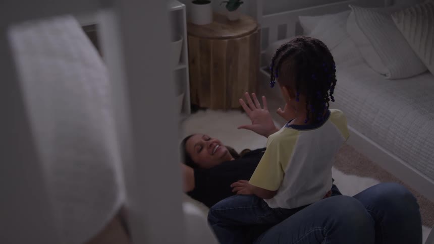 Child sitting on a womans lap lying on the floor interacting with hands