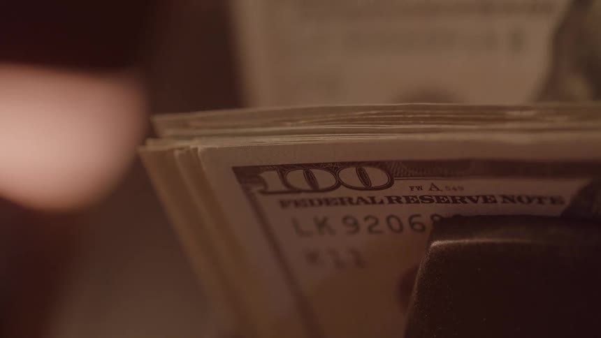A stack of crisp one hundred dollar bills being counted by a machine